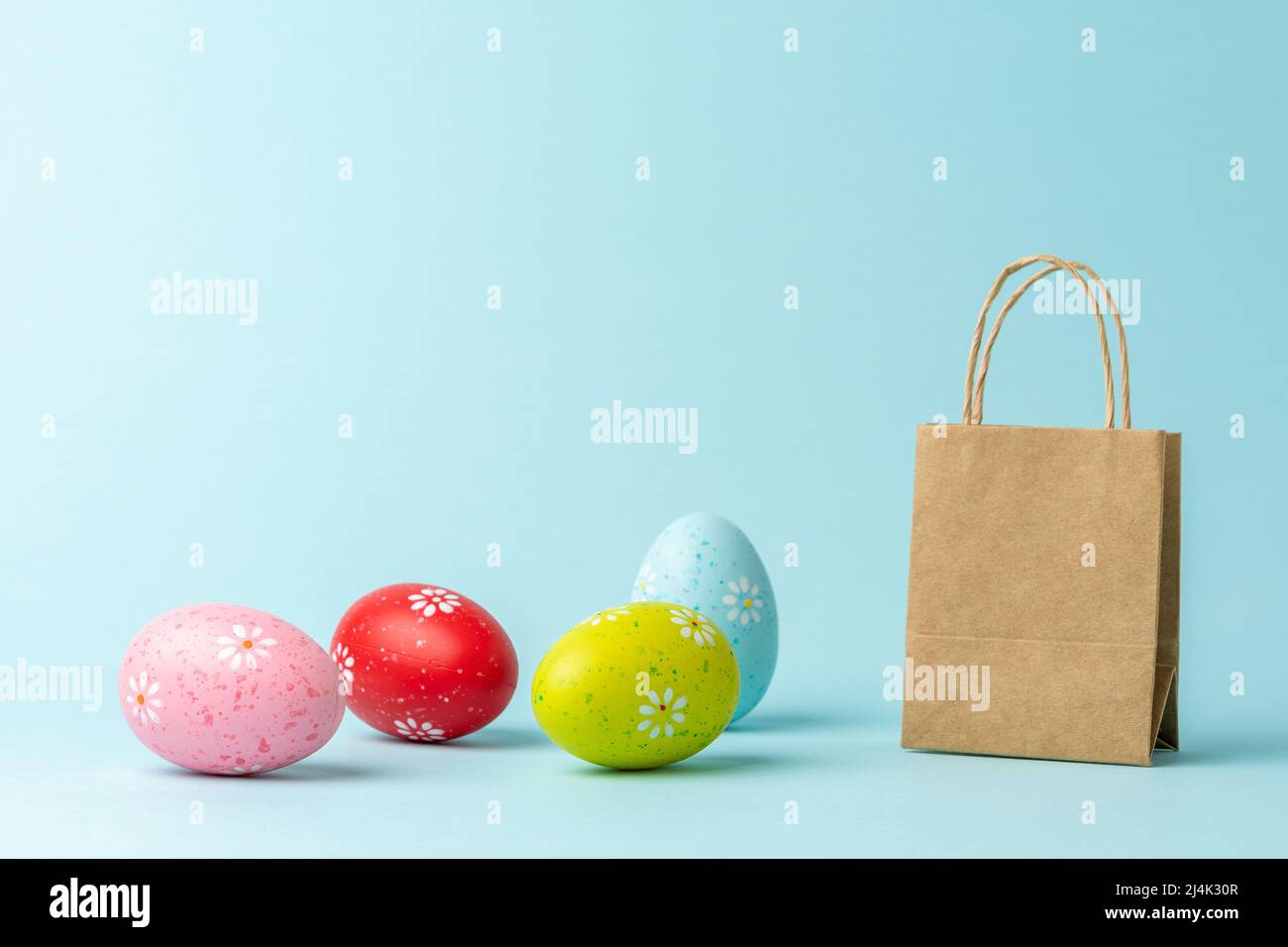 Different Easter eggs with shopping bag on blue background. Creative minimal shopping concept. Stock Photo