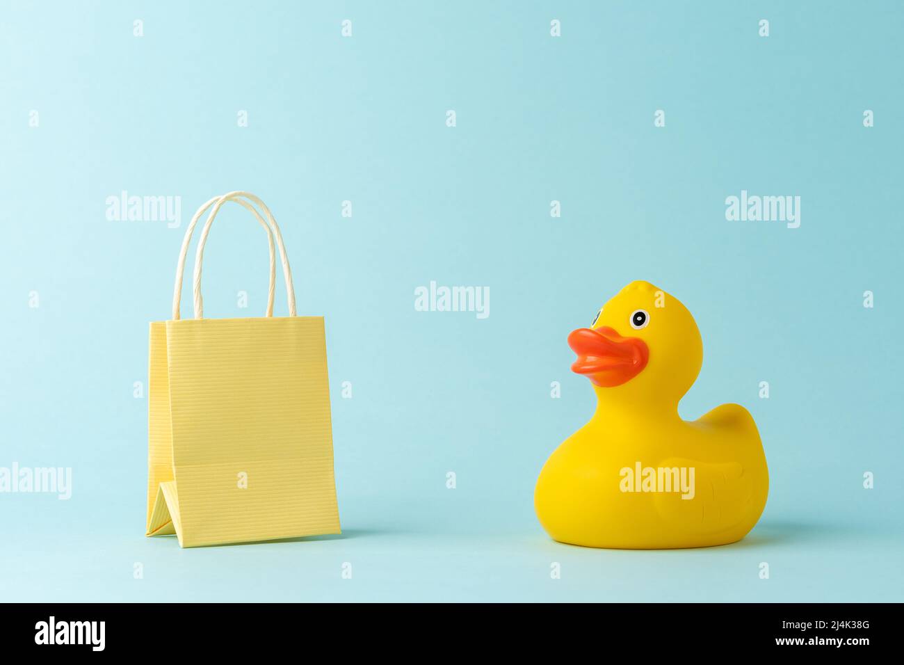 Rubber duck with shopping bag on blue background. Creative minimal shopping concept. Stock Photo
