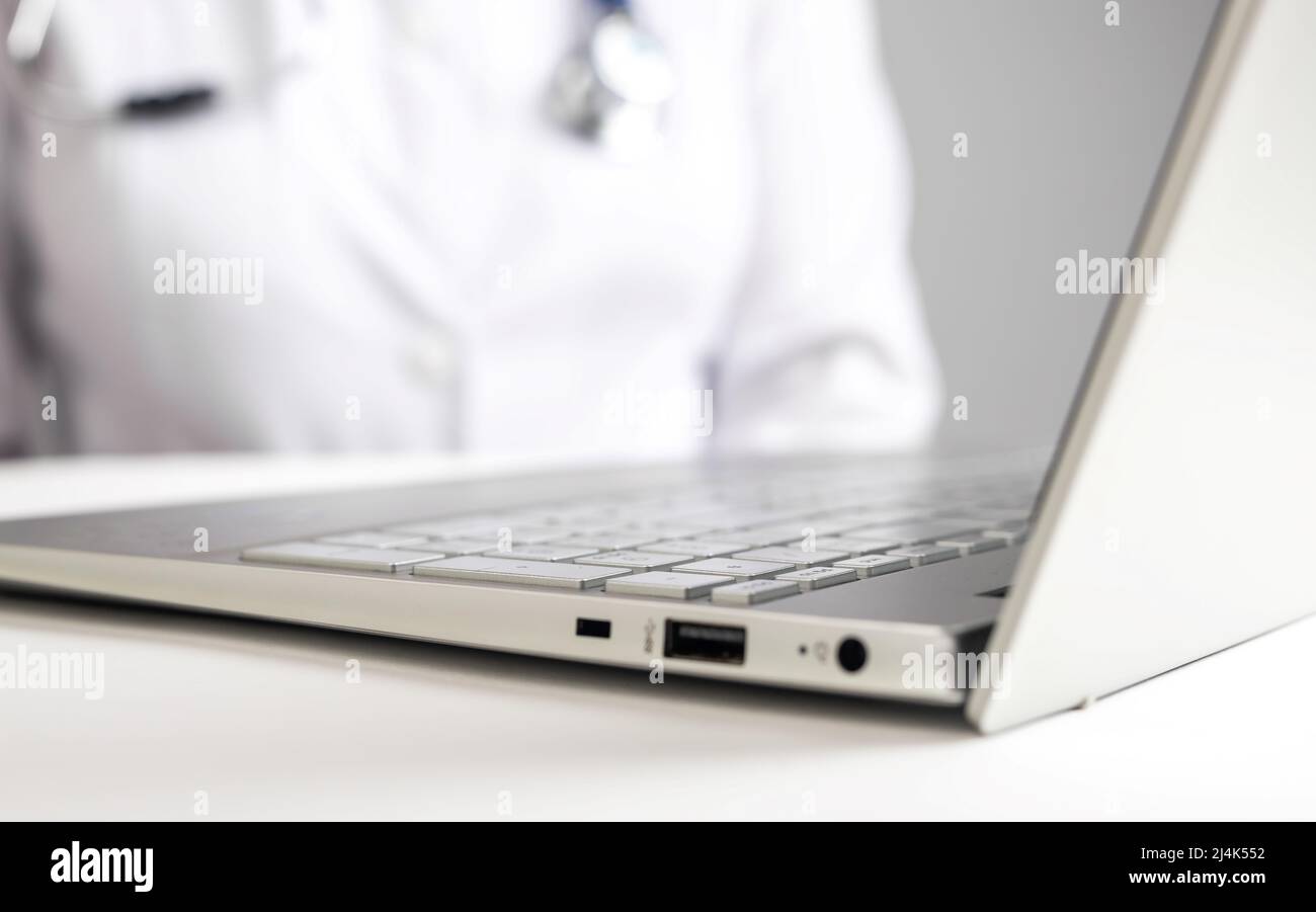 Doctor with stethoscope sitting at desk with laptop. Woman in lab coat giving online