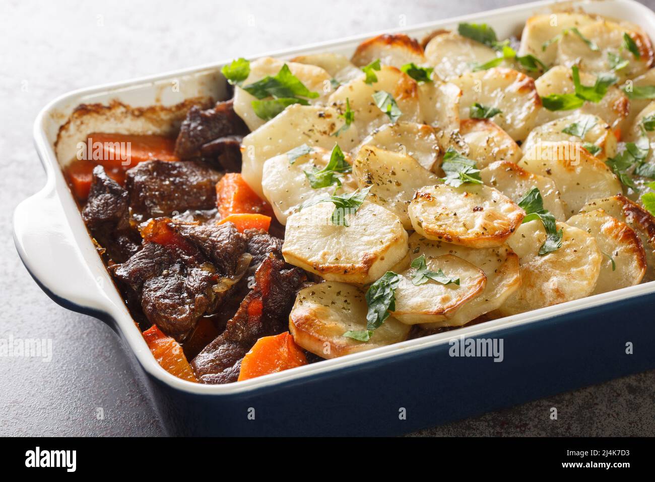 Lancashire Hot Pot, lamb and vegetables topped with sliced potatoes and oven baked closeup in the baking dish on the table. Horizontal Stock Photo