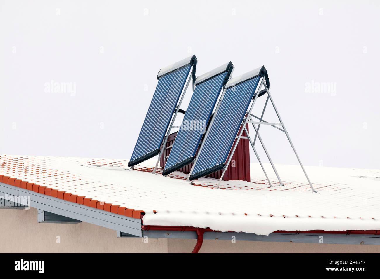 Snowy house roof in winter with solar panels for electric power generation Stock Photo