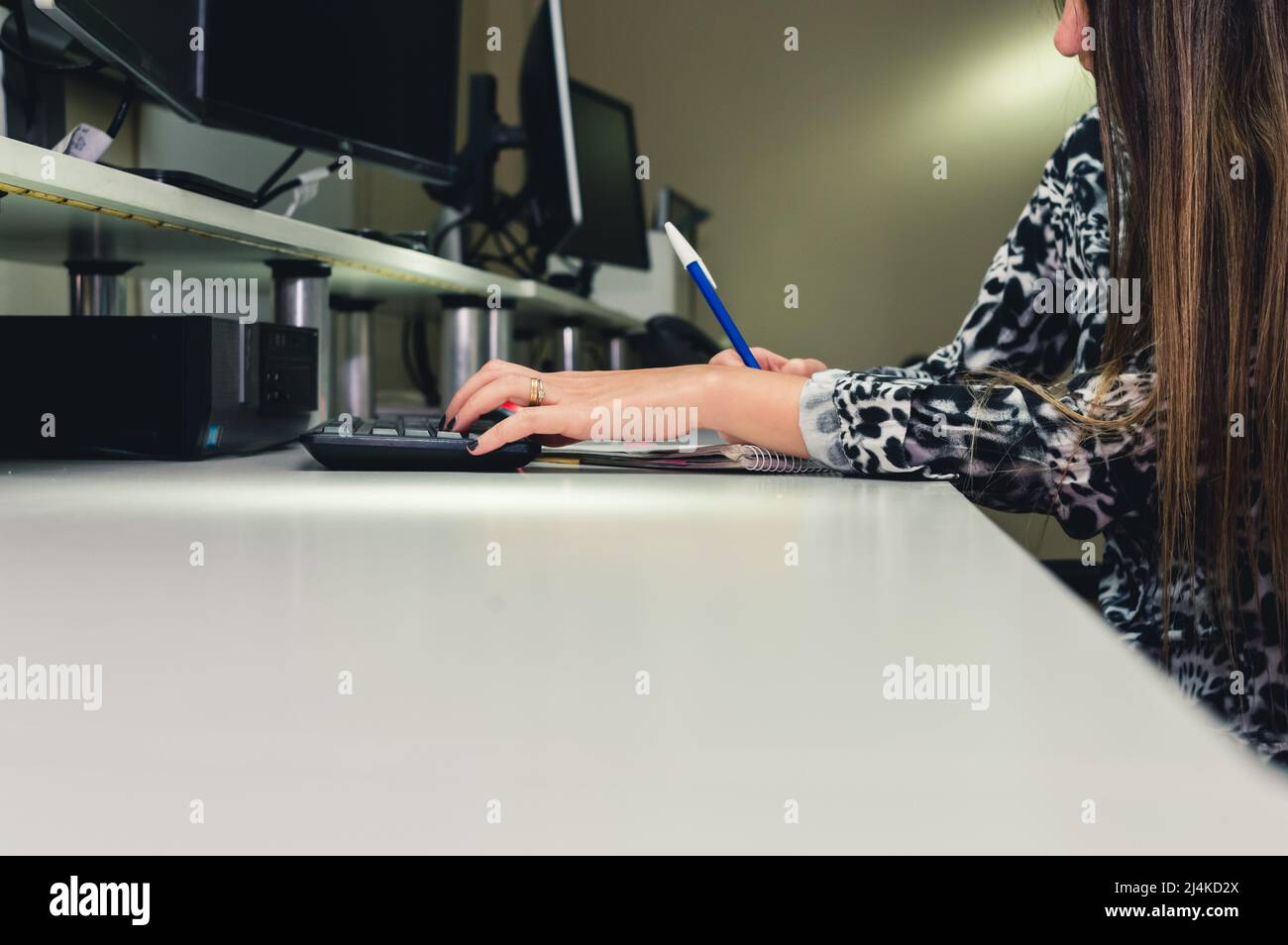 young female employee worker in office sitting using computer and writing notes from her clients, software programming office worker, copy space Stock Photo