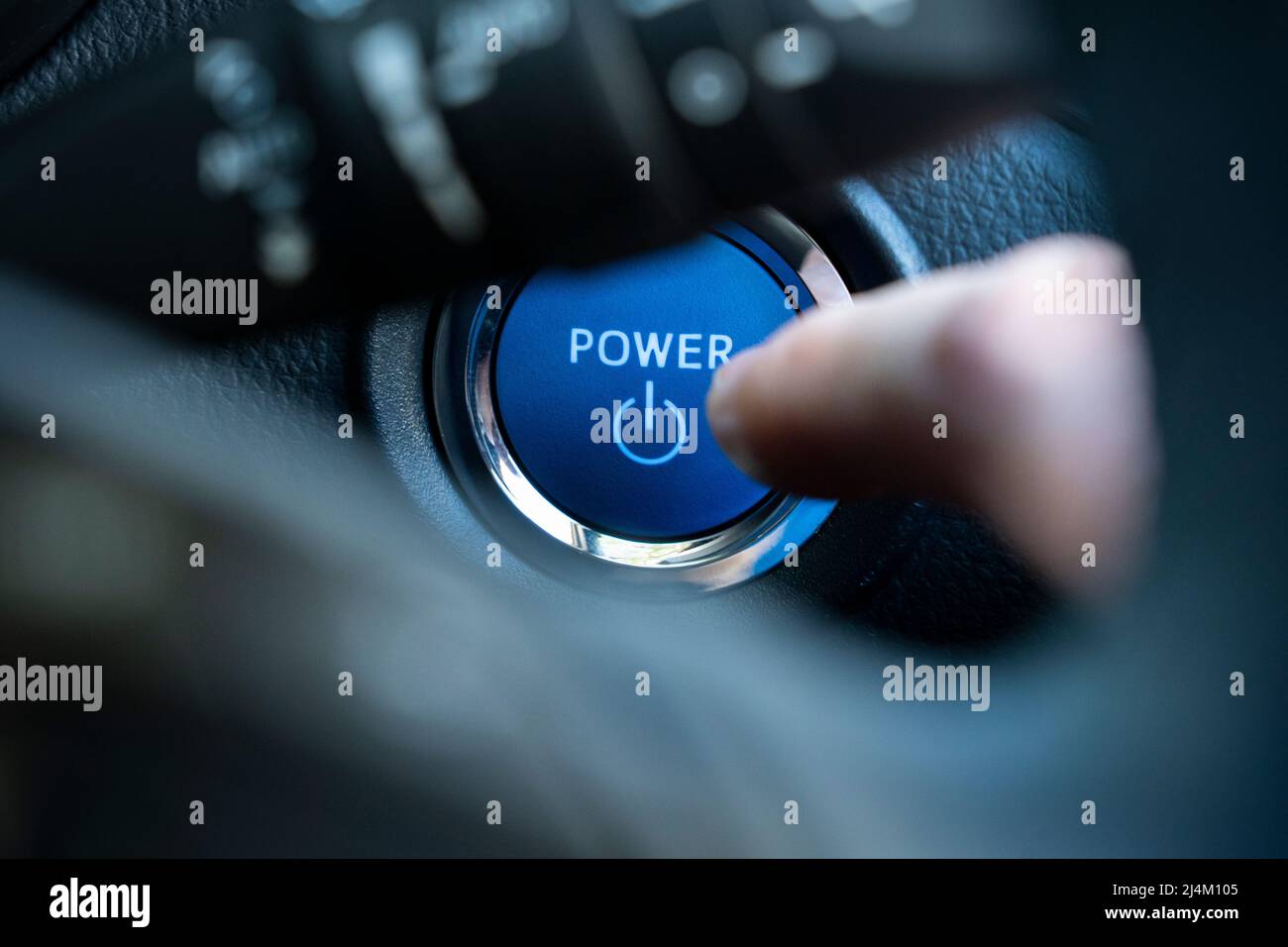 A closeup of a driver's finger pushing a keyless power button on the dashboard of a 2021 Toyota CH-R, a self charging petrol hybrid car. UK Stock Photo