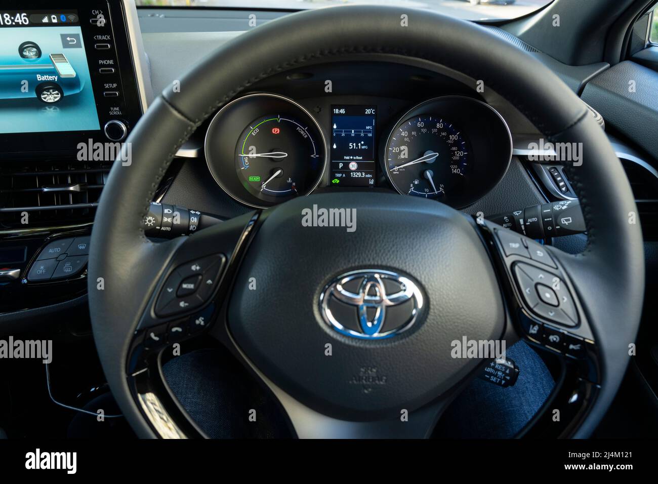 Steering wheel with the Toyota logo and the dashboard of a hybrid petrol 2021 Toyota CH-R car. UK Stock Photo