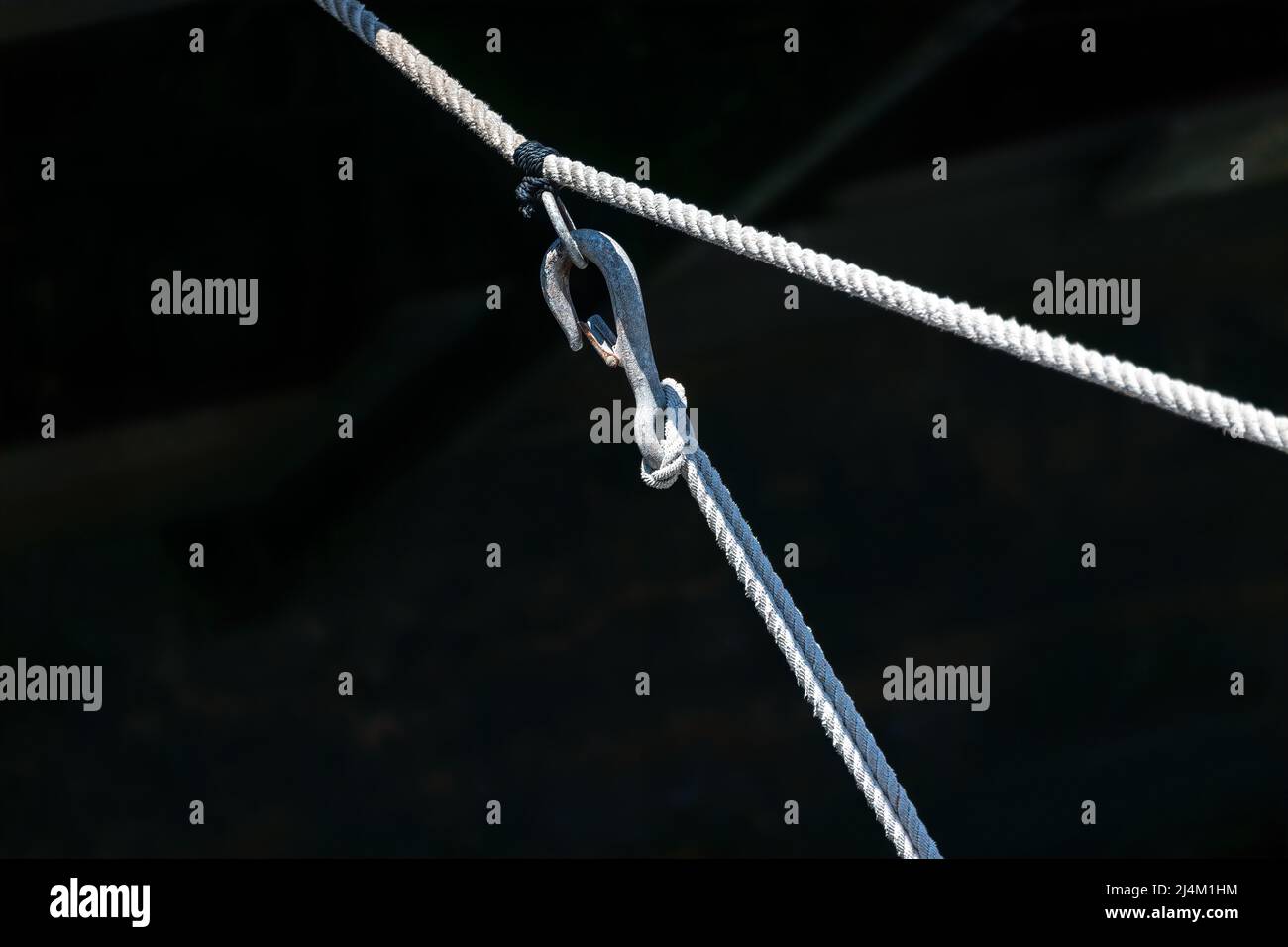 Small watercraft docking line rig in bright sunlight over shaded harbor