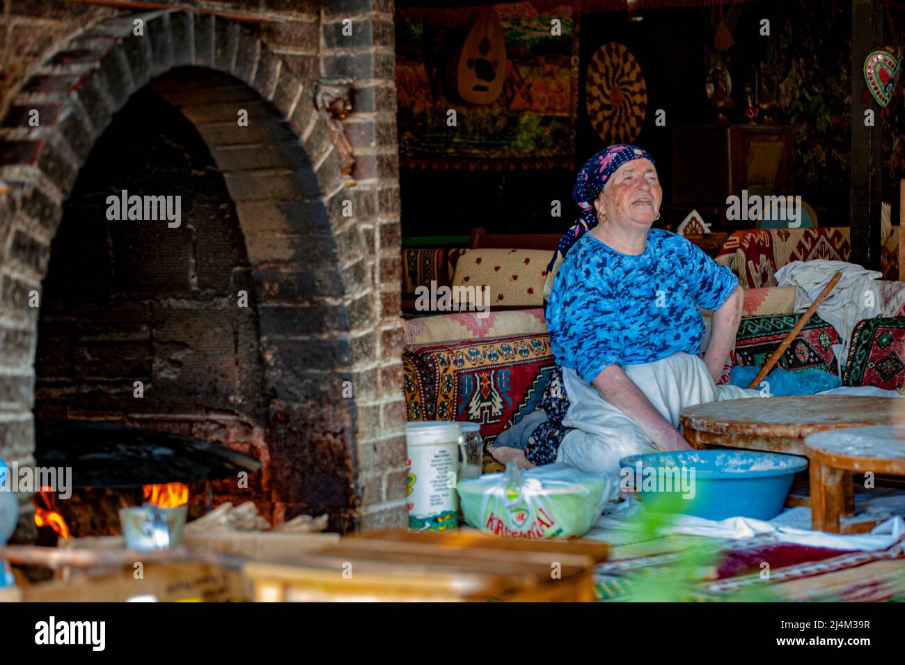Older Turkish woman sits while at work making food at an eatery in Ephesus, Turkey. Stock Photo