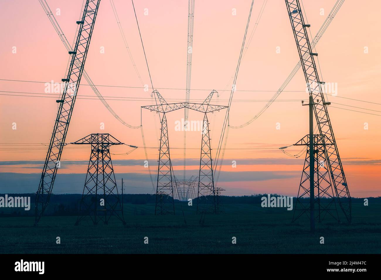 A line of power poles standing in a field and going into the distance beyond the horizon. Stock Photo