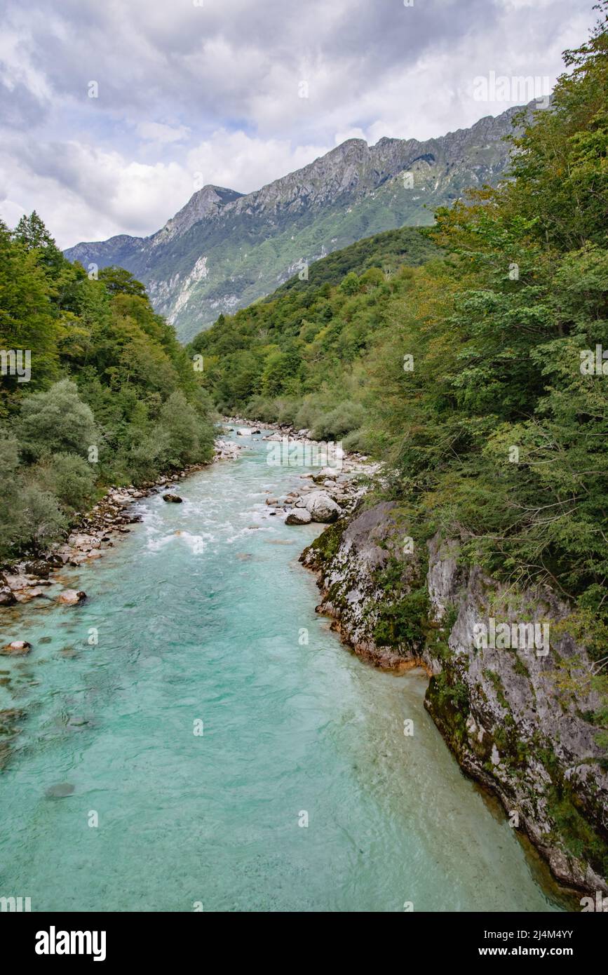 View of the Slovenian river Socha with mountains and cloudy sky in the background, portrait format Stock Photo