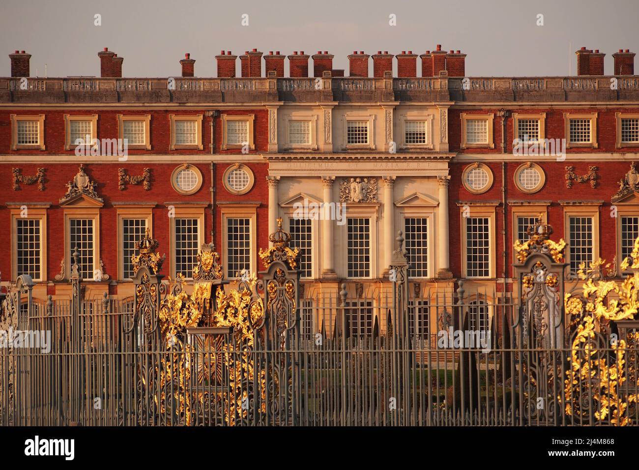 A view the red brick, ornate chimneys, walls, windows and railings of Hampton Court Palace, London, Surrey, England, the home of King Henry VIII Stock Photo