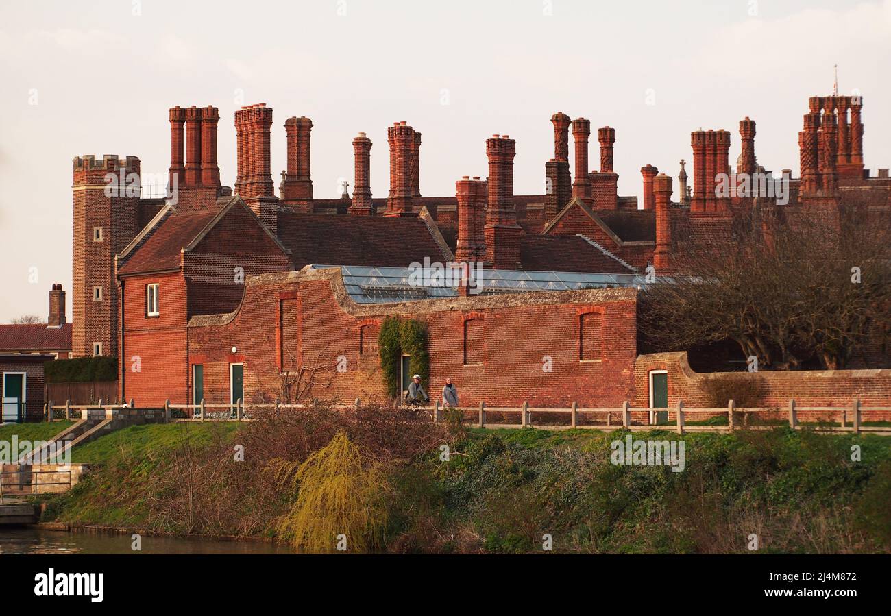 A view of some of the red brick, ornate chimneys, walls and windows of Hampton Court Palace, the home of King Henry VIII from the River Thames Stock Photo