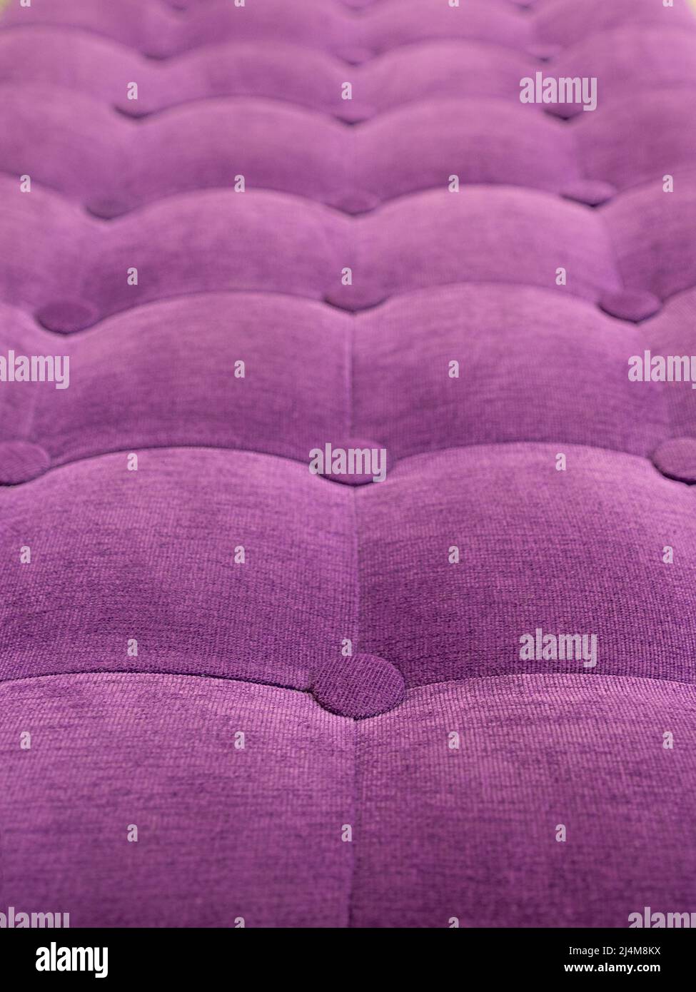 upholstery of velour buttoned purple violet color fabric, wall pattern. Elegant vintage quilted sofa background. Interior Stock Photo