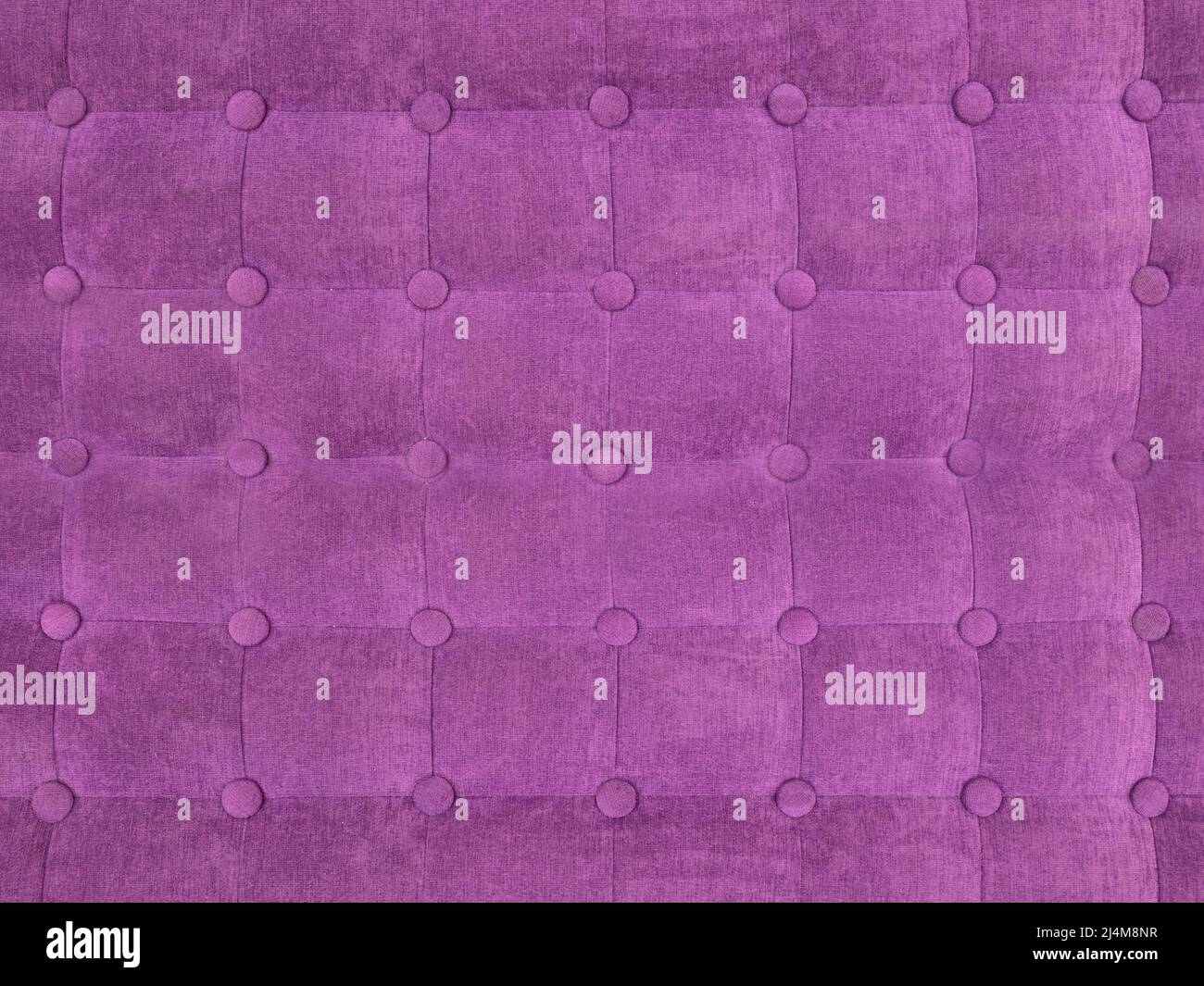 upholstery of velour buttoned purple violet color fabric, wall pattern. Elegant vintage quilted sofa background. Interior Stock Photo