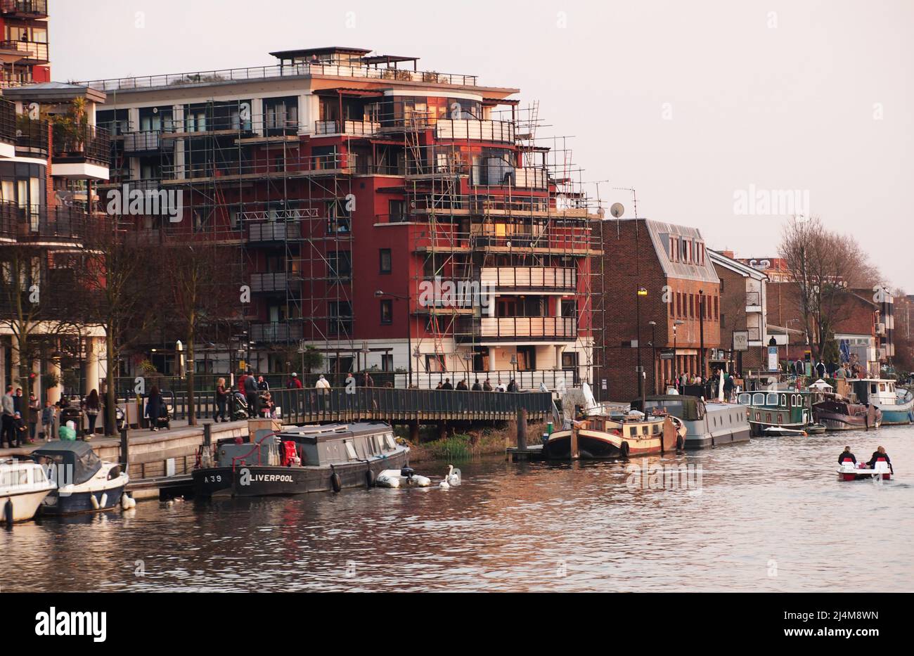 A view of Kingston upon Thames from a river cruise boat on the River Thames showing a bustling, busy, river and bank path and waterside buildings Stock Photo