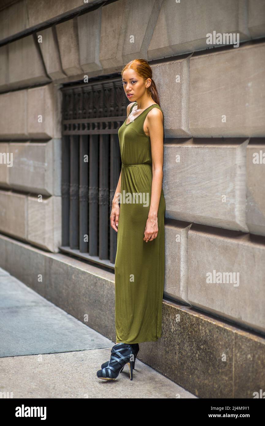 Woman Relaxing on Street. Dressing in a green, long Maxi Tank Dress,  black dress sandals, a young black lady is standing by old fashion style window Stock Photo