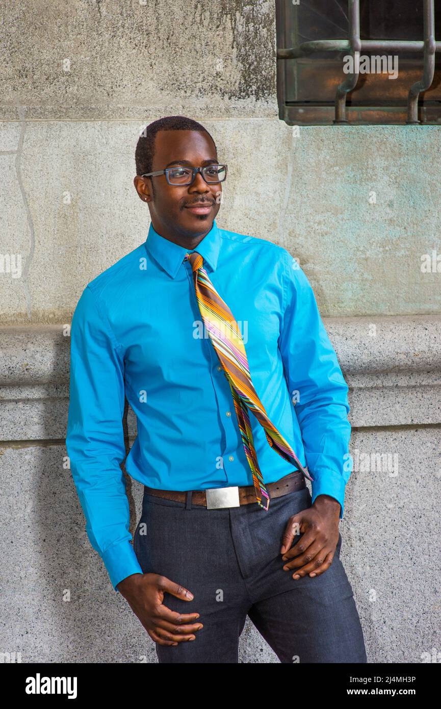 Dressing in a light blue shirt, a colorful pattern tie, gray pants, wearing  glasses, a young black college student is standing by a pattern wall on ca  Stock Photo - Alamy