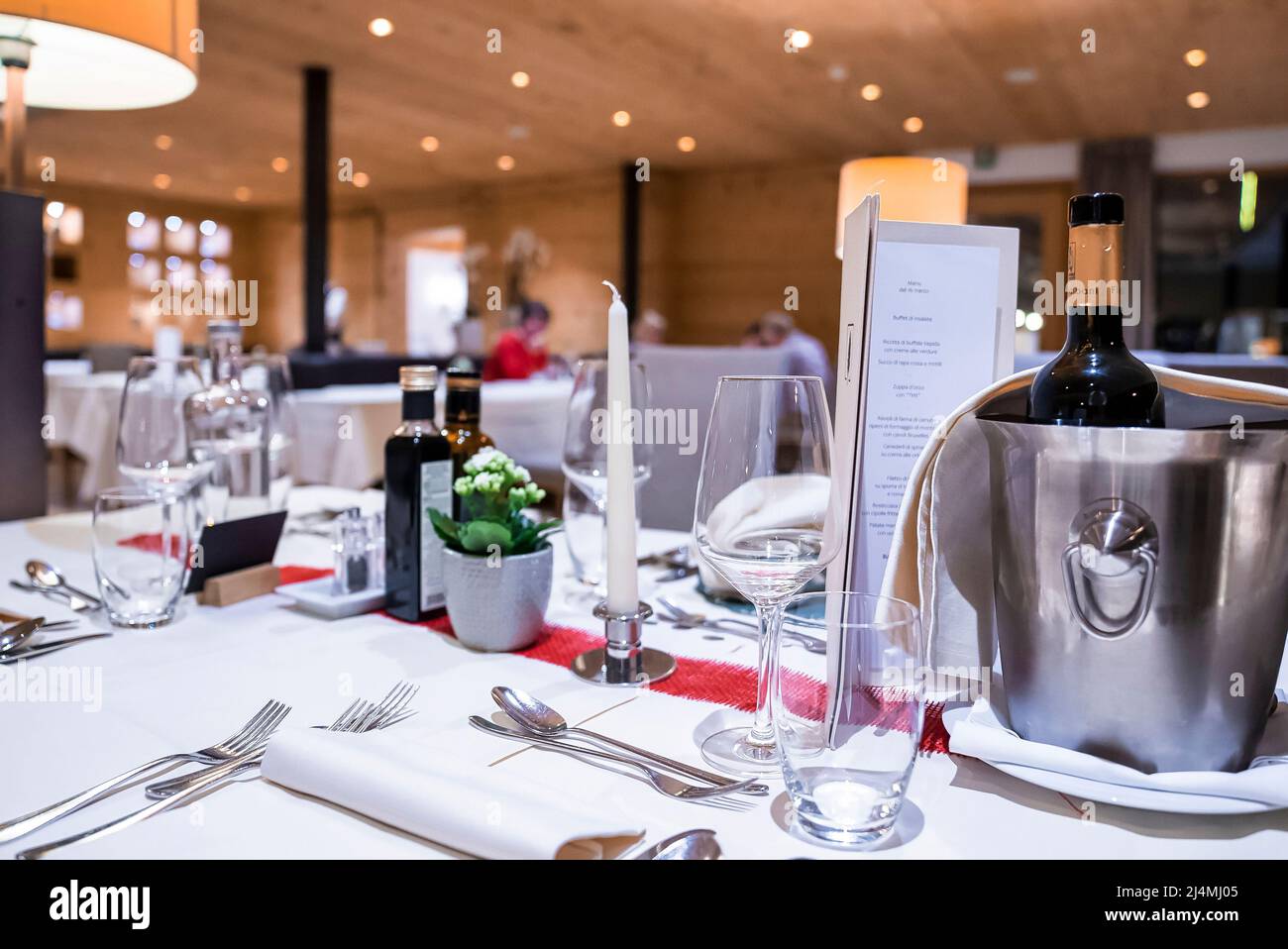Wine bottle in ice bucket on table with elegant place setting in luxury