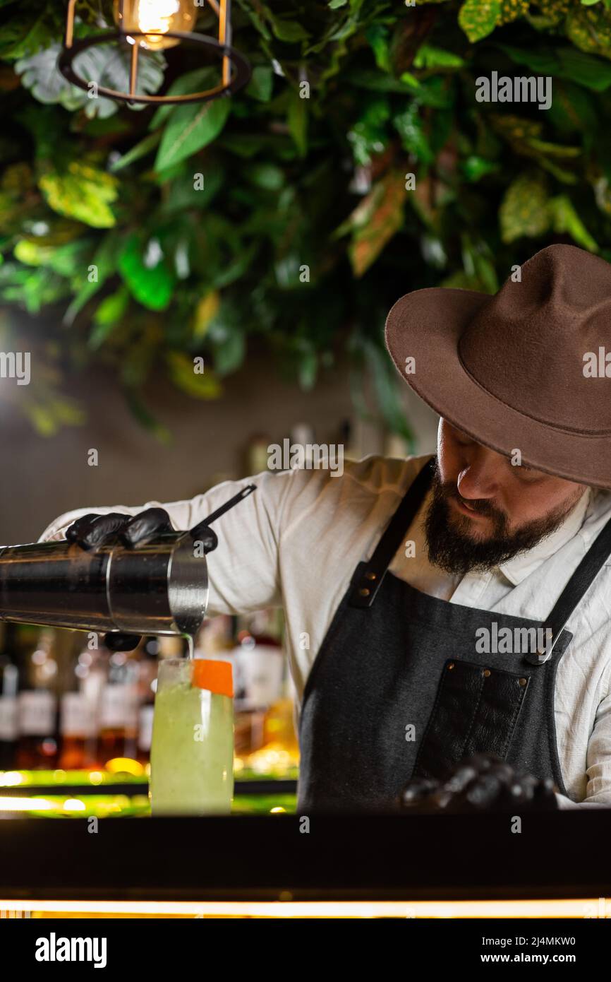 Bartender pouring an alcohol from the measuring glass cup through the