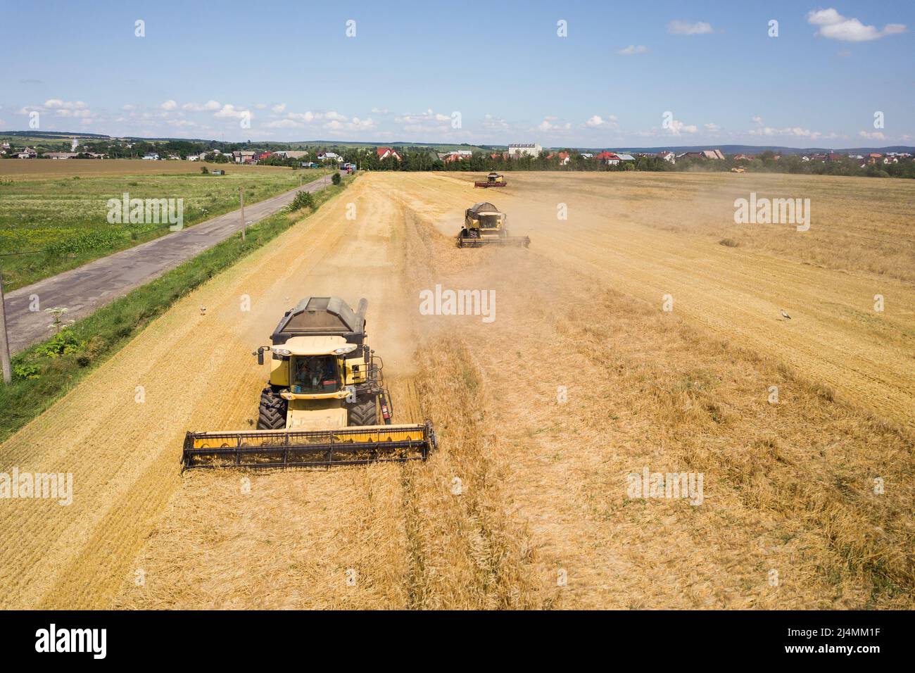 Aerial view of combine harvesters harvesting large yellow ripe wheat ...