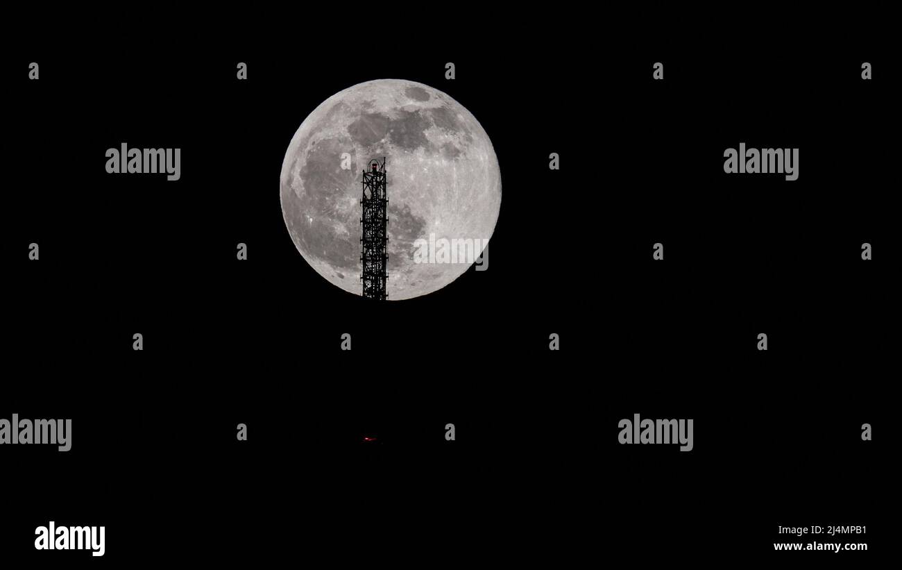 super full moon behind the Stuttgart TV Tower - the antenna is touching the moon. Stock Photo