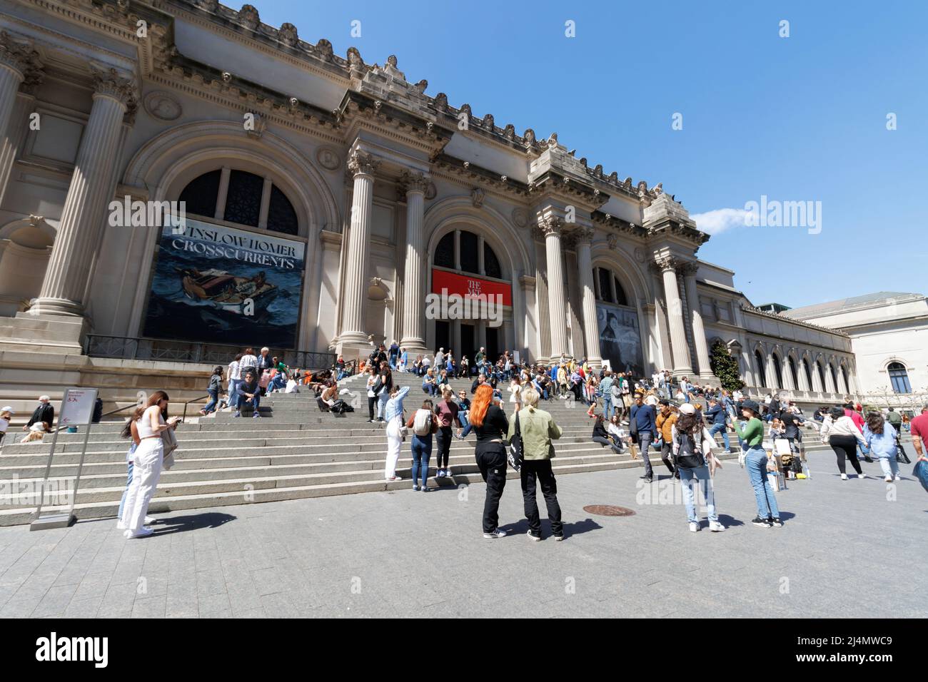 People walk and sit around the grand staircase entrance to the Metropolitan Museum of Art on fifth avenue on a beautiful Spring day Stock Photo