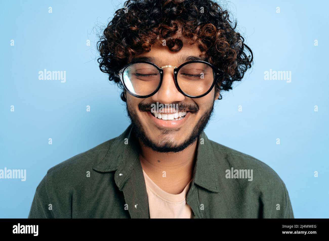 Close-up face of a curly charismatic indian or arabian guy with glasses ...