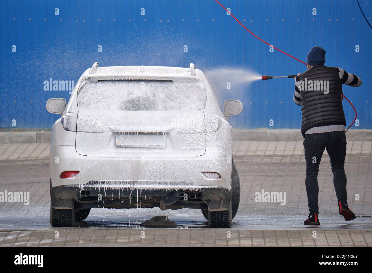 Closeup of male driver washing his car with contactless high pressure