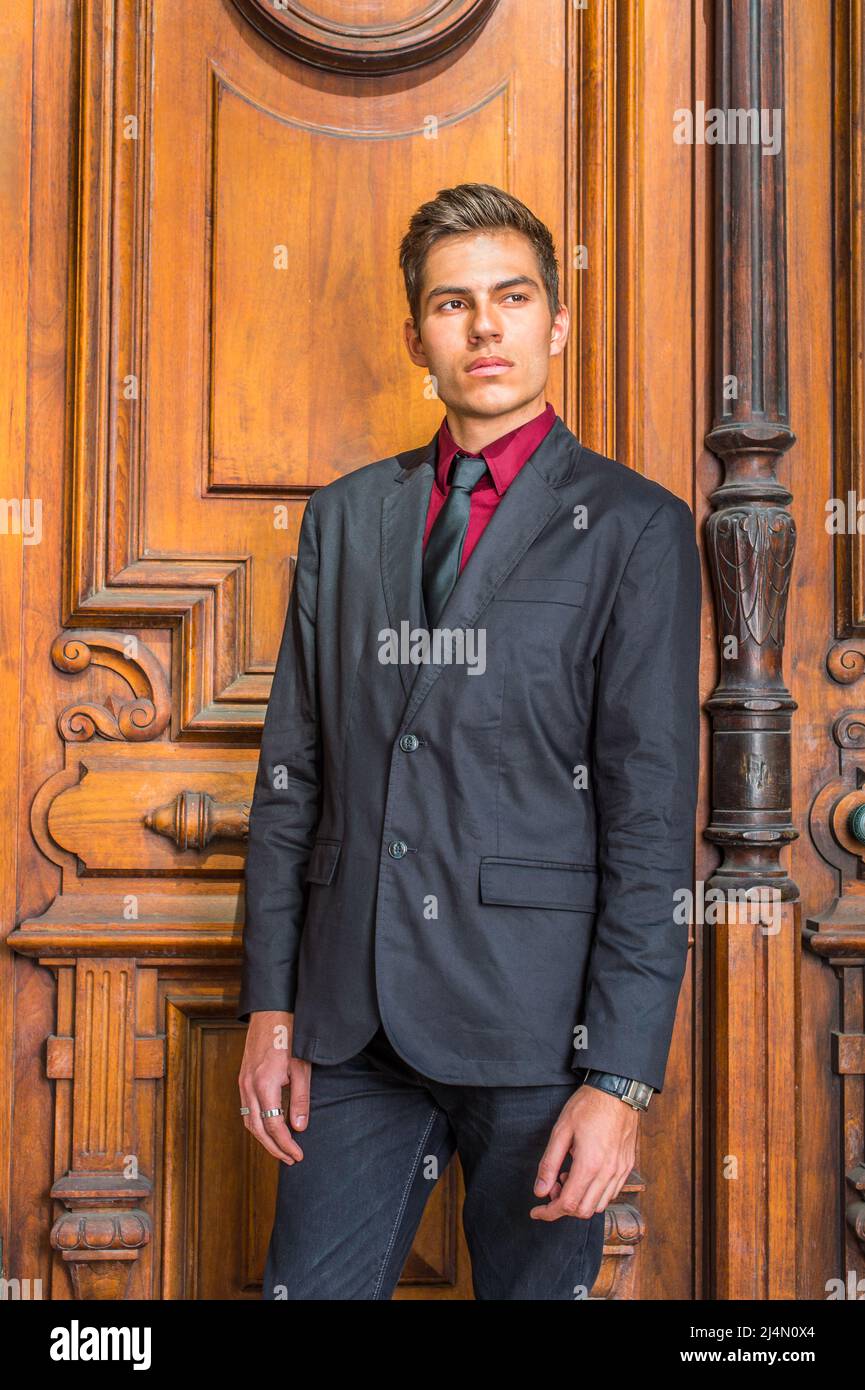 Dressing in a red undershirt, a black blazer, black jeans, a black tie, a  handsome college student is standing in the front o old fashion style doo  Stock Photo - Alamy