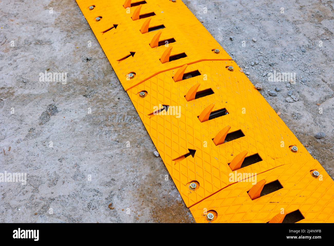 Spike barrier or strip on the road for control the traffic. yellow  mechanical spike barrier Stock Photo - Alamy
