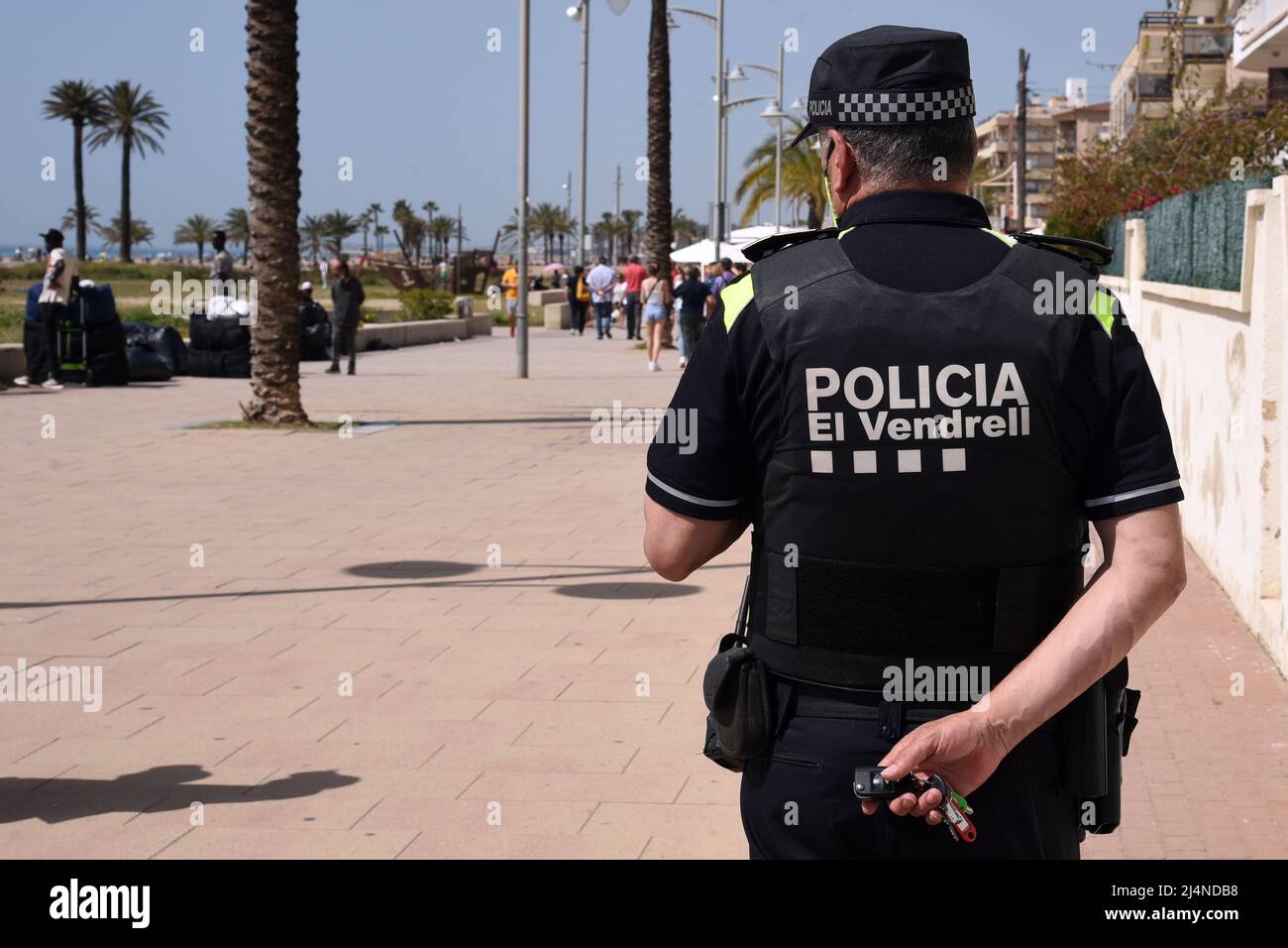 Vendrell, Spain. 16th Apr, 2022. A local police officer observes some  vendors who collect their products on the Paseo Maritimo Street. The  Vendrell local police fights daily against the illegal street vendors