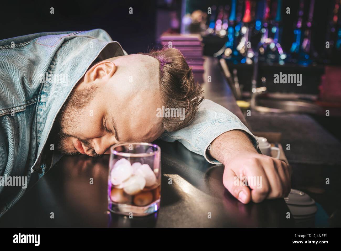 Alcoholism, depressed young man sleep on table while drinking alcoholic ...
