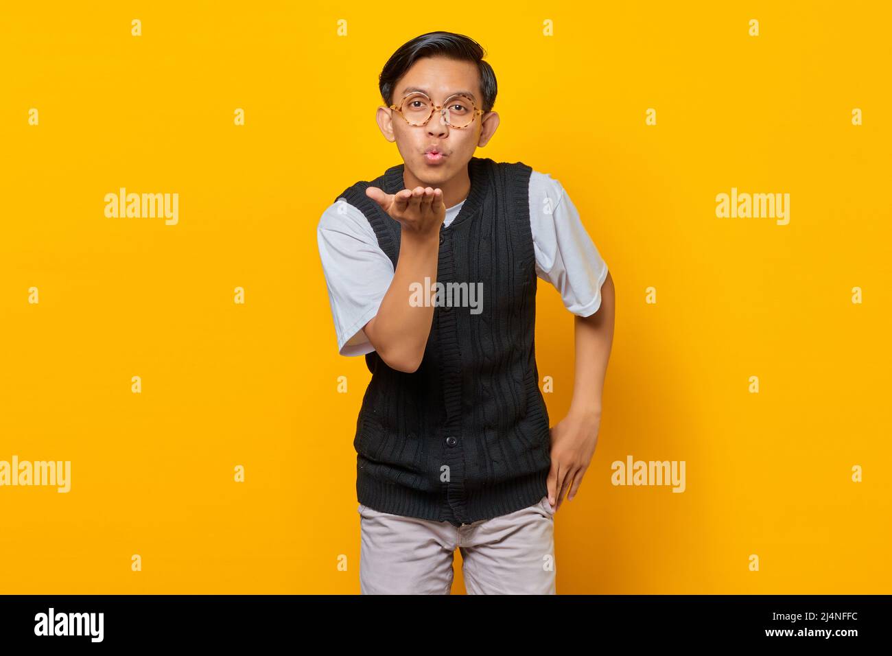 Portrait of charming young Asian man holding palms sending air kiss to girlfriend Stock Photo