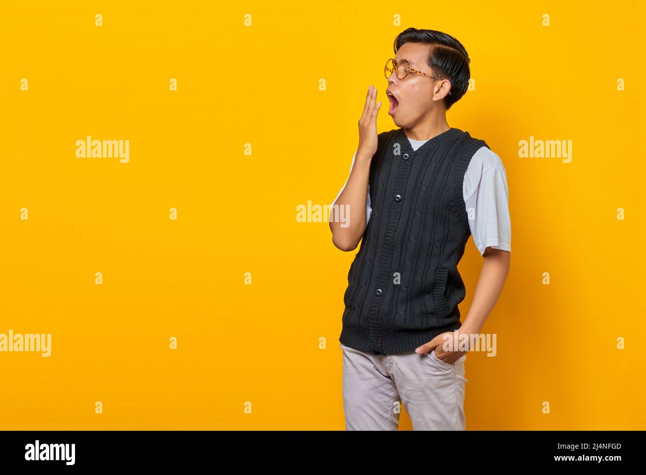 Portrait of handsome young Asian man feeling sleepy and covering mouth with hand Stock Photo