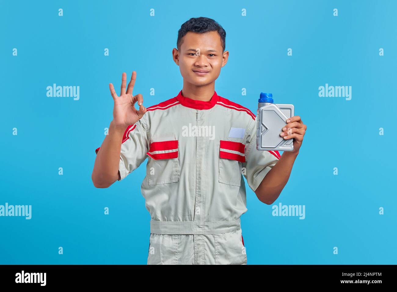 Portrait of smiling young Asian mechanic holding plastic bottle of ...