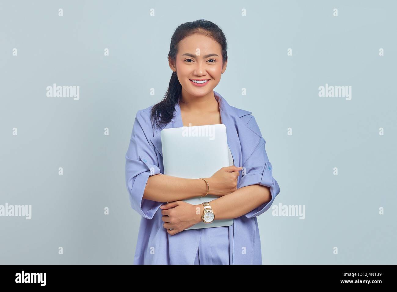 Portrait of cheerful young Asian woman holding a laptop and looking at ...