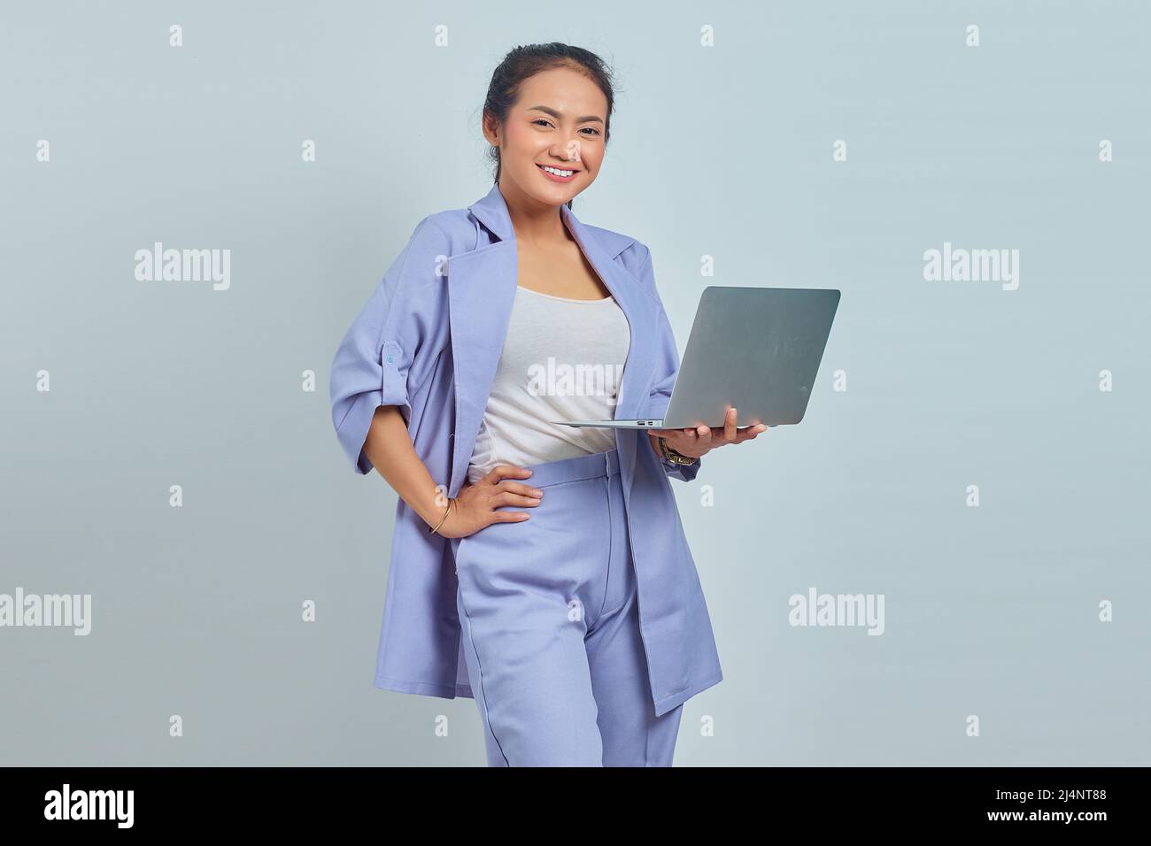 Portrait of cheerful young Asian woman using laptop and looking at ...