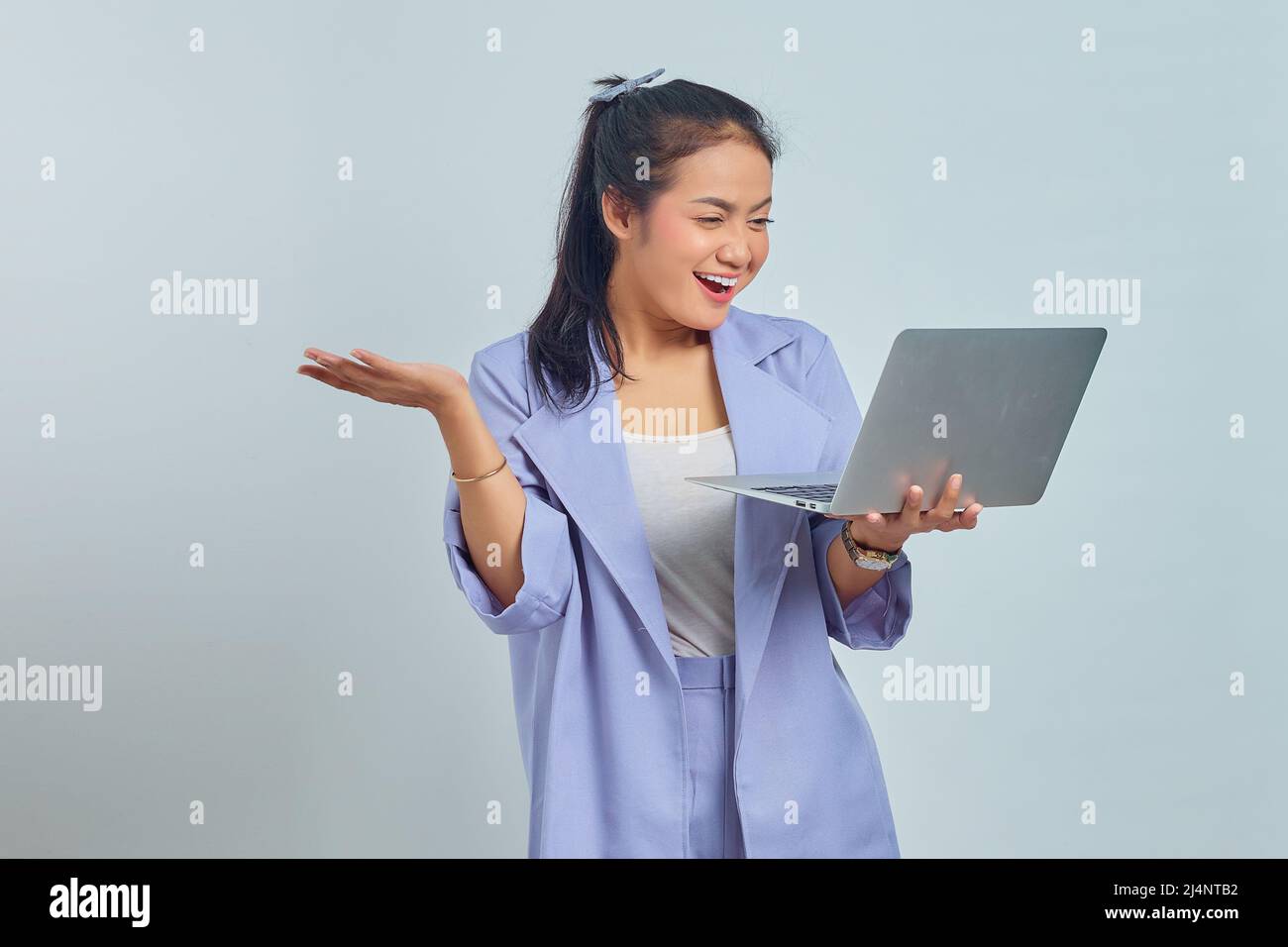 Portrait of smiling young Asian woman looking at laptop and celebrating ...