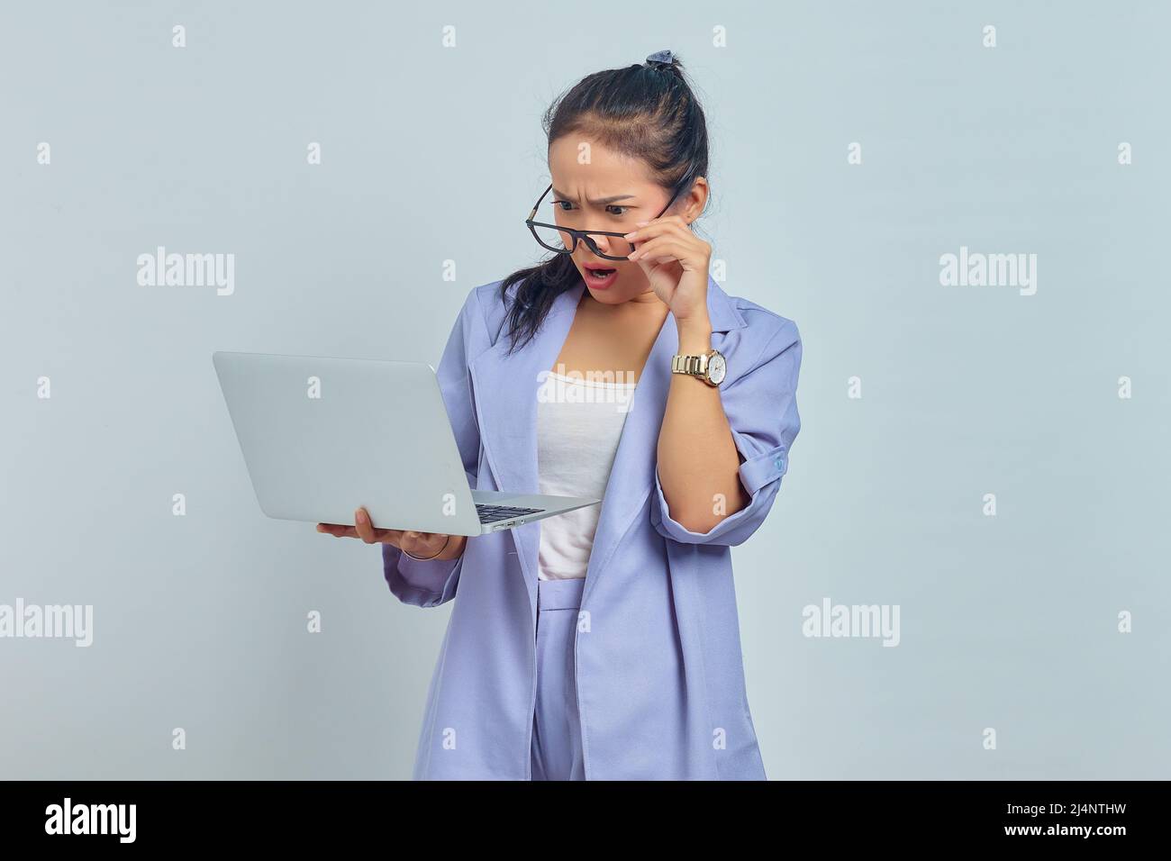 Portrait of surprised young Asian woman holding laptop and take off ...