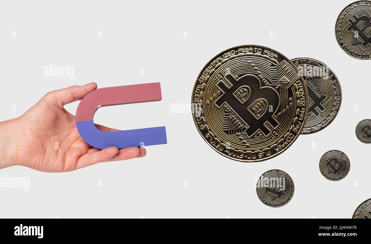 Hand holding magnet and attracting bitcoins. Digital, virtual currency. Finance, tax and investment concept. High quality photo Stock Photo