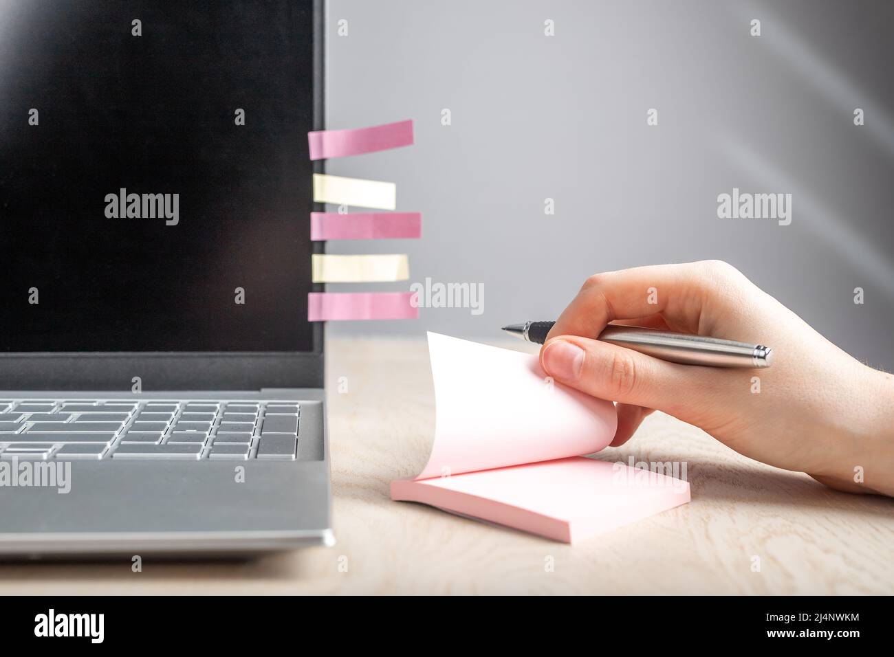 Woman hand taking memo notes at sticky papers. Female sitting at table with laptop and recording with pen key words and phrases, plans, thoughts. High quality photo Stock Photo
