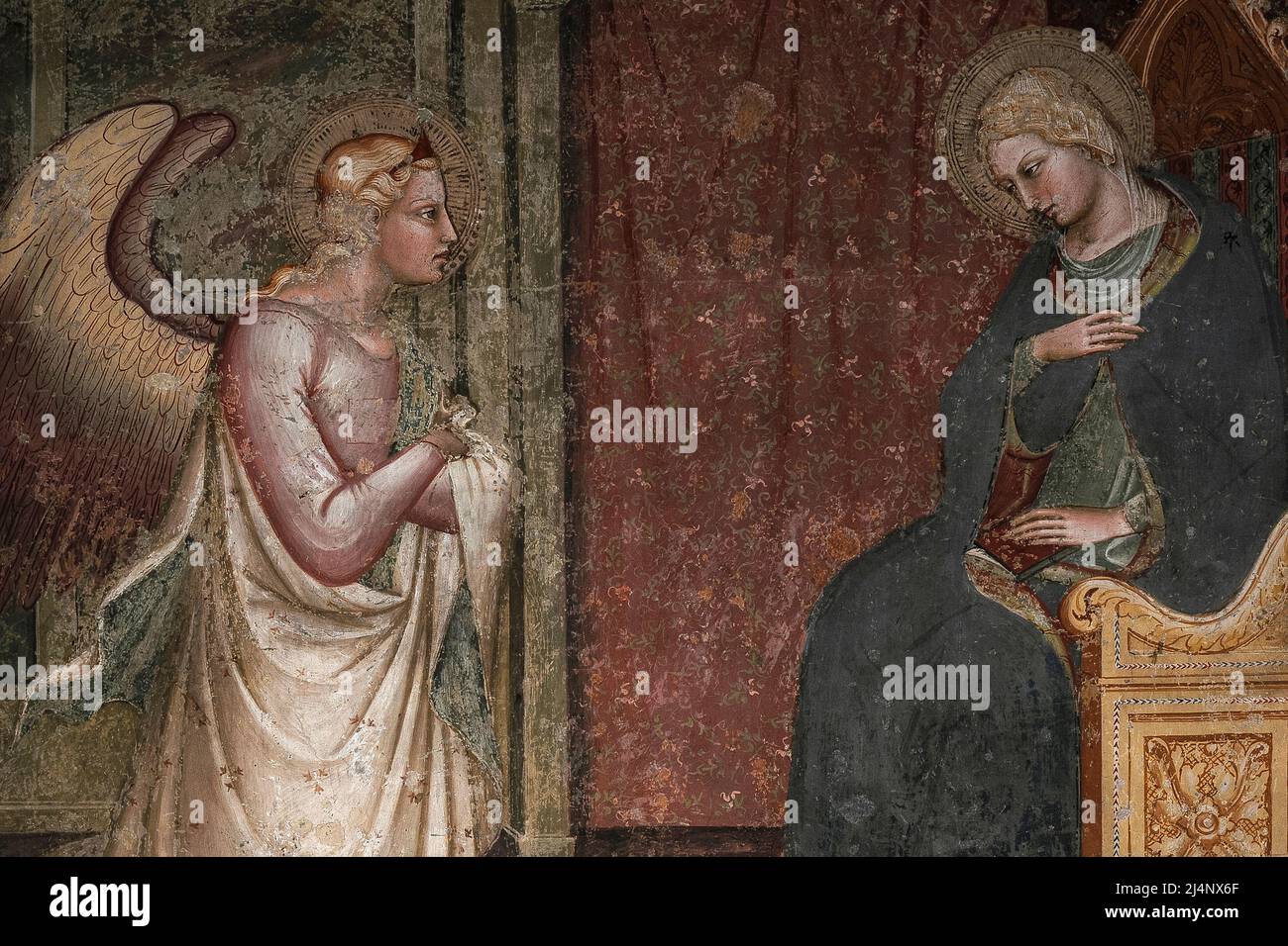 Archangel Gabriel kneels before a seated Virgin Mary.  Late 1300s or early 1400s Annunciation fresco in the Chiesa di San Domenico at Arezzo, Tuscany, Italy.  The work is attributed to locally-born early Renaissance artist Spinello Aretino (c. 1350 - c. 1410), an influential painter who frescoed churches throughout Tuscany in the late 14th and early 15th centuries. Stock Photo