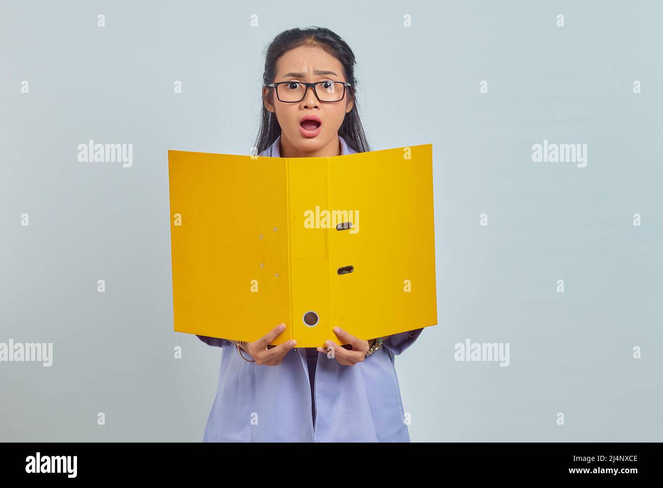Portrait of surprised young Asian business woman holding yellow folder ...