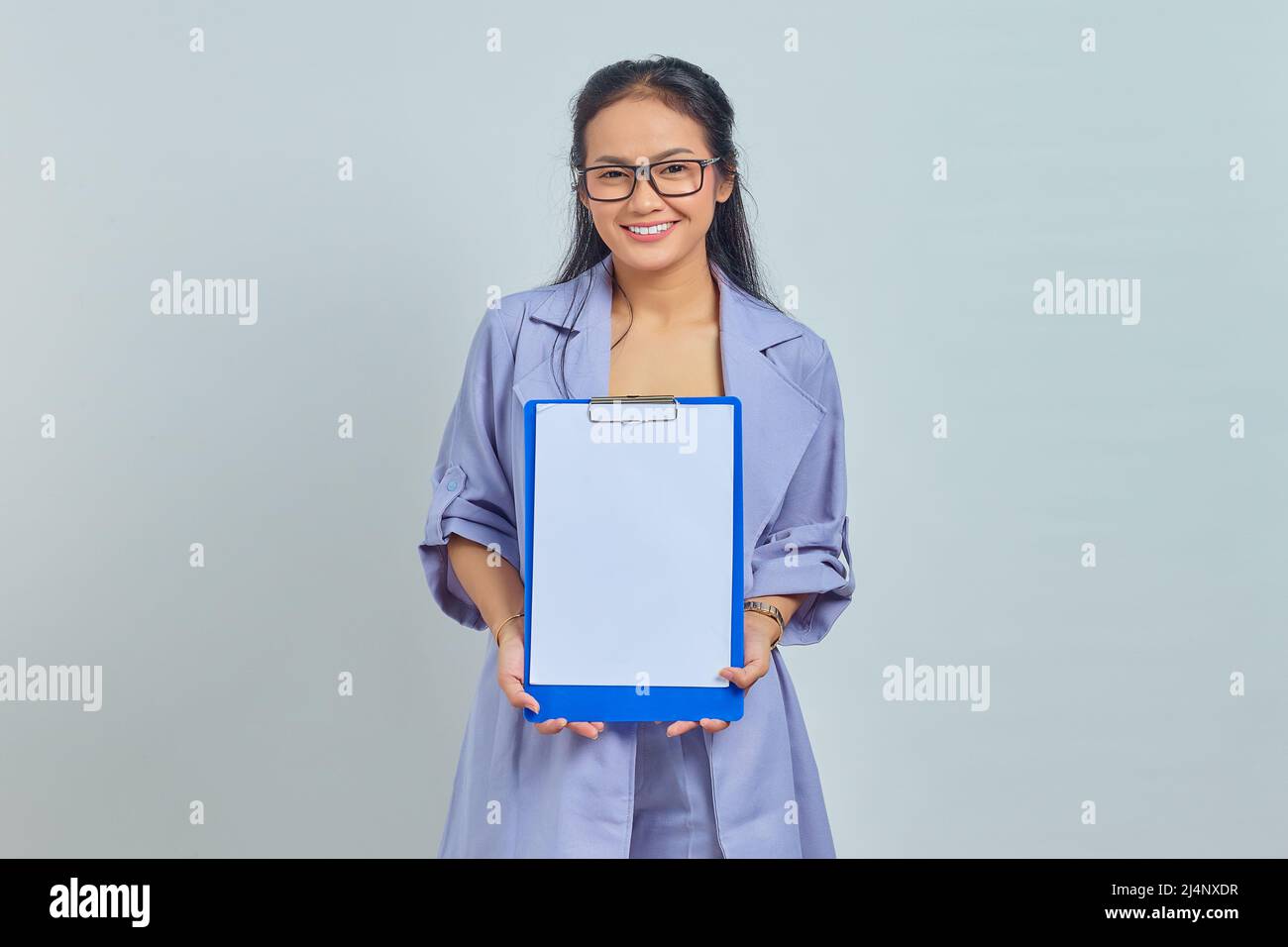 Portrait of cheerful young Asian business woman showing blank clipboard ...