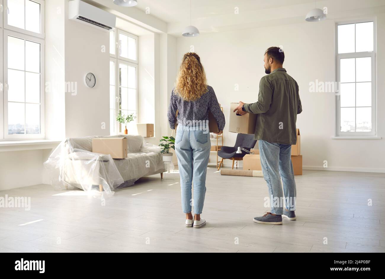 Young couple holding boxes standing in their new house or apartment on moving day Stock Photo