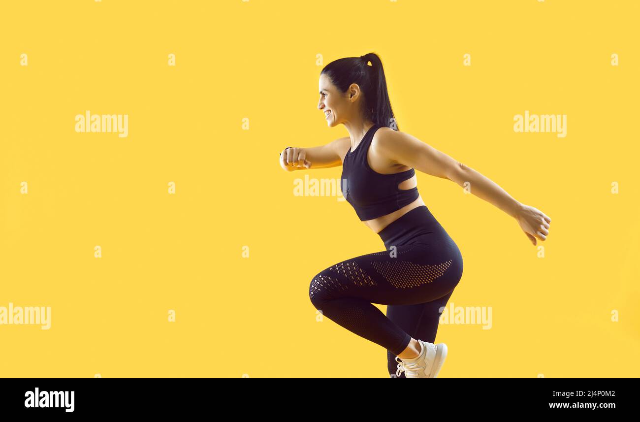 Beautiful smiling female athlete running and jumping isolated on vivid