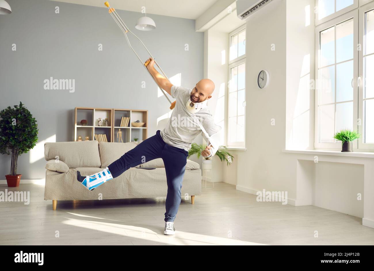 Funny positive man with numerous physical injuries having fun during rehabilitation at home. Stock Photo