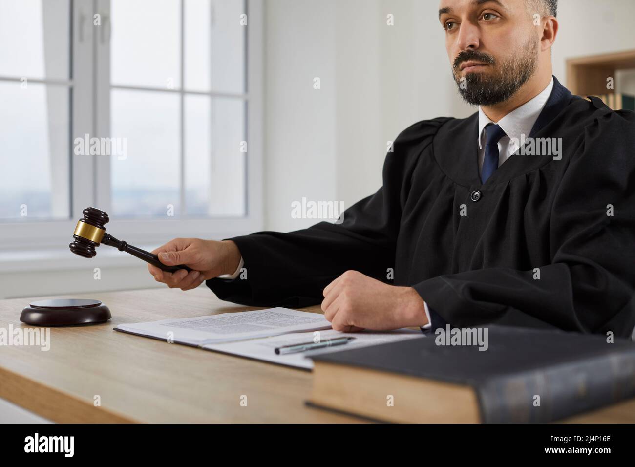 Fair serious male judge passes sentence and decides to close case during court hearing. Stock Photo