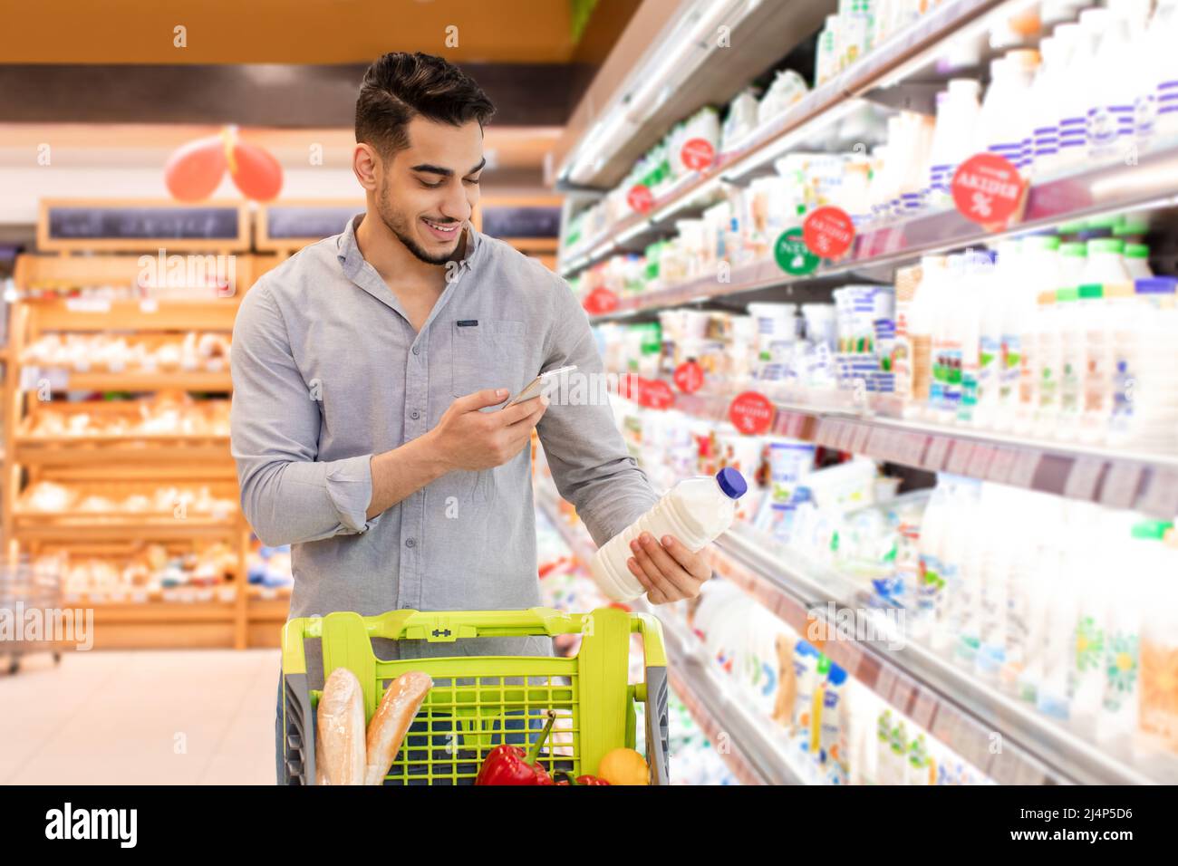 Arabic Guy Scanning Milk Using Phone Shopping Groceries In Supermarket Stock Photo