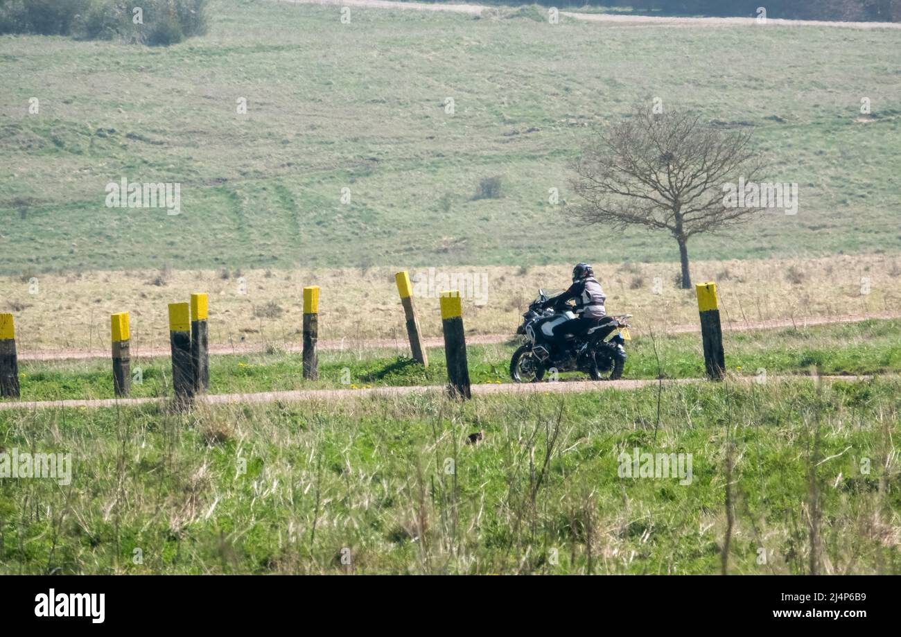 a motor cyclist (biker) riding their offroad motorbike along a stone