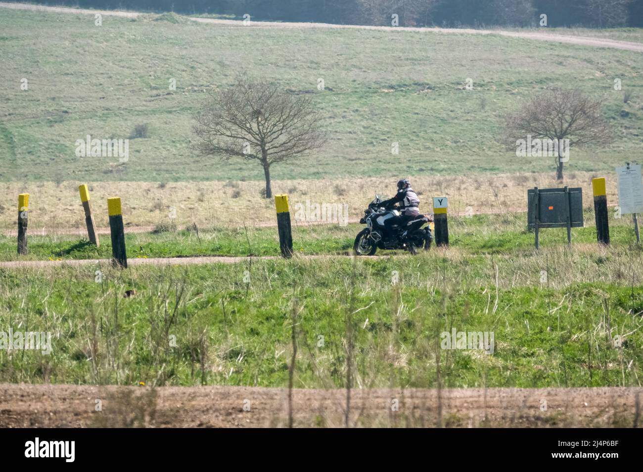 a motor cyclist (biker) riding their offroad motorbike along a stone
