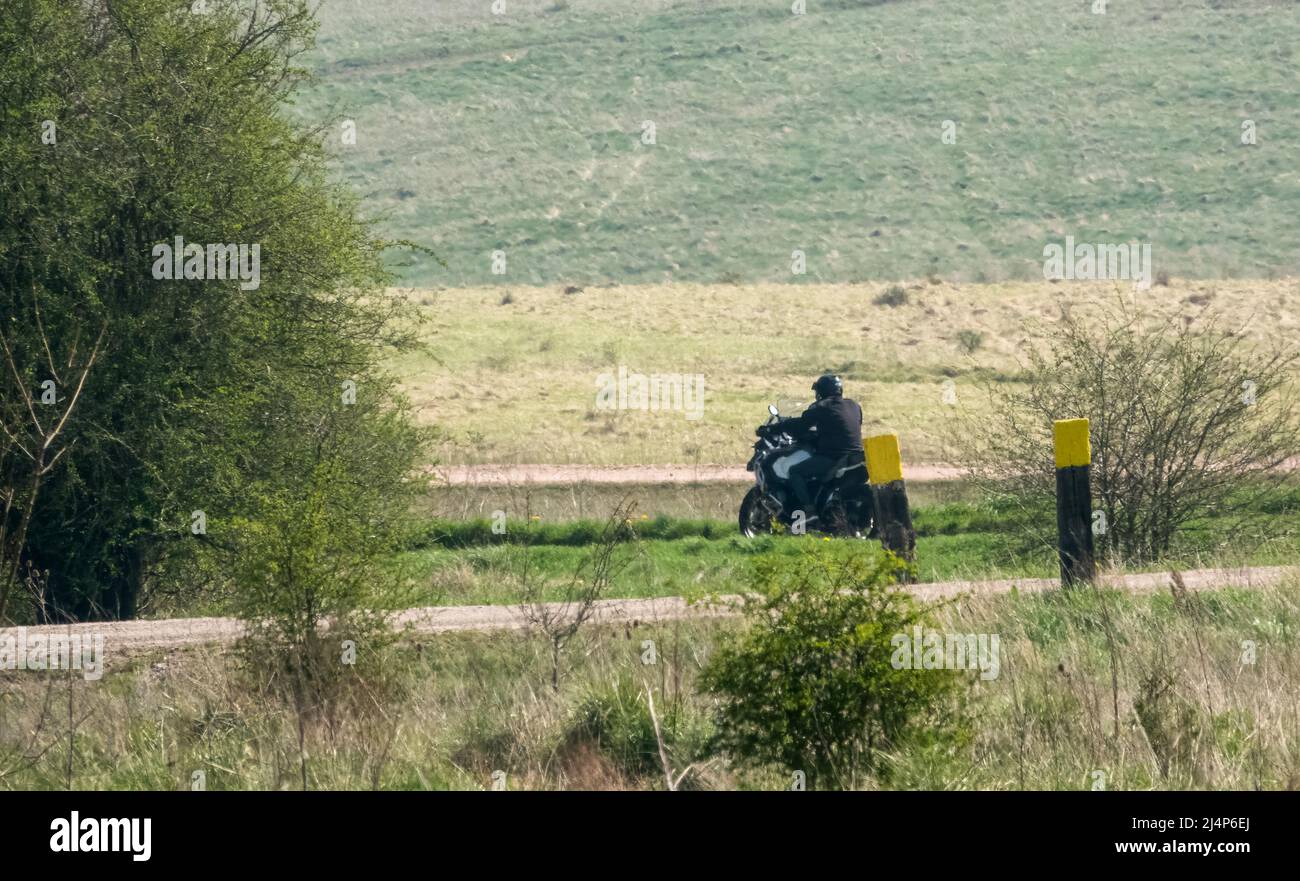 a motor cyclist (biker) riding their offroad motorbike along a stone